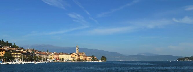 Fit beliebte Urlaubsziele am Gardasee -  Mit einer Fläche von 370 km² ist der Gardasee der größte See Italiens. Es liegt am Fuße der Alpen und erstreckt sich über drei Staaten: Lombardei, Venetien und Trentino. Die maximale Tiefe des Sees beträgt 346 m, er hat eine längliche Form und sein nördliches Ende ist sehr schmal. Dort ist der See von den Bergen der Gruppo di Baldo umgeben. Du trittst aus deinem gemütlichen Hotelzimmer und es begrüßt dich die warme italienische Sonne. Du blickst auf den atemberaubenden Gardasee, der in zahlreichen Blautönen schimmert - von tiefem Dunkelblau bis zu funkelndem Türkis. Majestätische Berge umgeben dich, während die Brise sanft deine Haut streichelt und der Duft von blühenden Zitronenbäumen deine Nase kitzelt. Du schlenderst die malerischen, engen Gassen entlang, vorbei an farbenfrohen, blumengeschmückten Häusern. Vereinzelt unterbricht das fröhliche Lachen der Einheimischen die friedvolle Stille. Du fühlst dich wie in einem Traum, der nicht enden will. Jeder Schritt führt dich zu neuen Entdeckungen und Abenteuern. Du probierst die köstliche italienische Küche mit ihren frischen Zutaten und verführerischen Aromen. Die Sonne geht langsam unter und taucht den Himmel in ein leuchtendes Orange-rot - ein spektakulärer Anblick.